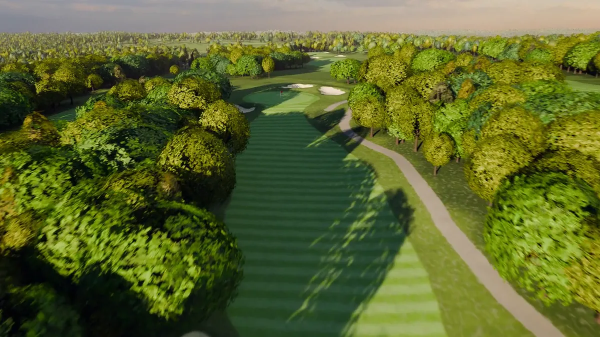 A golf hole from the air: a mown fairway running between trees to a green with two bunkers behind it, in low evening light.
